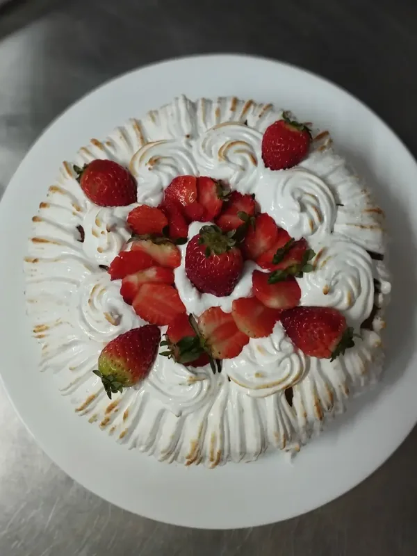 Bolo coberto de merengue maçaricado e morangos, visto de cima